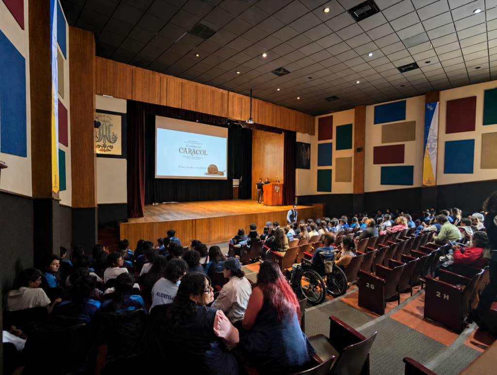 Proyección de El camino del caracol en un auditorio lleno de estudiantes