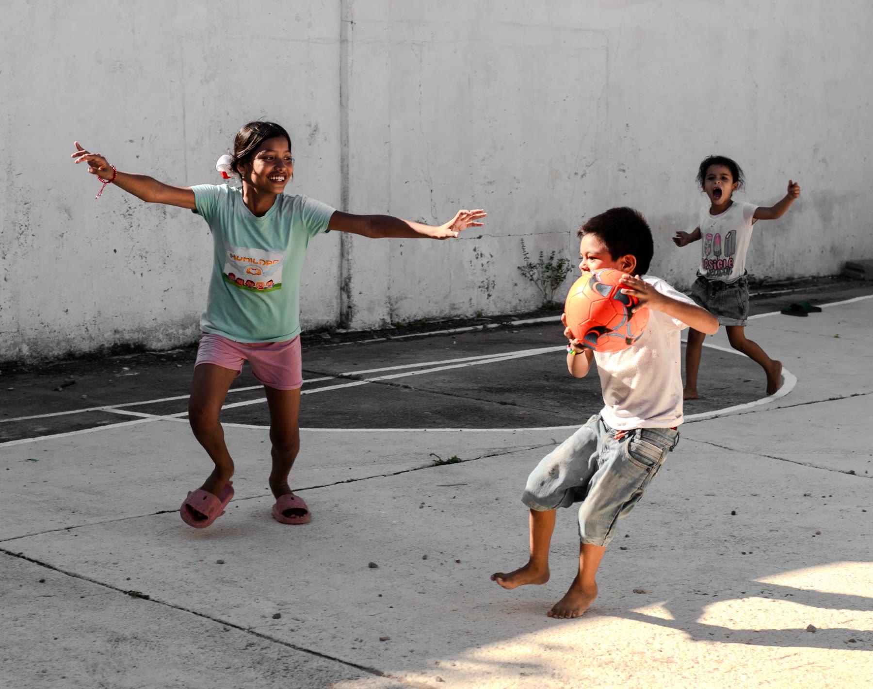 Niñas y niños jugando con un balón en una cancha